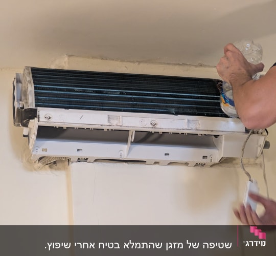 אדם מנקה מזגן עם בקבוק מים